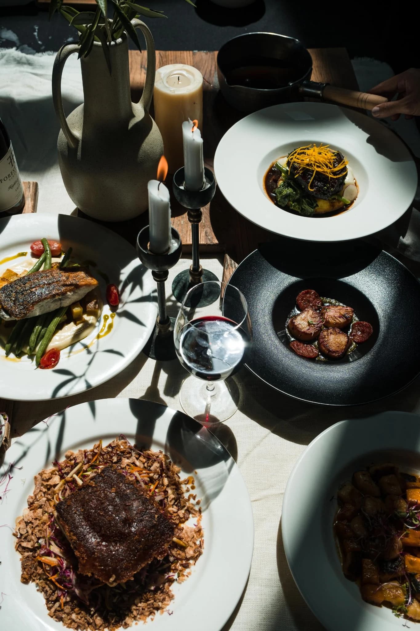 Stół z kilkoma daniami, świecami i kieliszkiem wina — FORMA